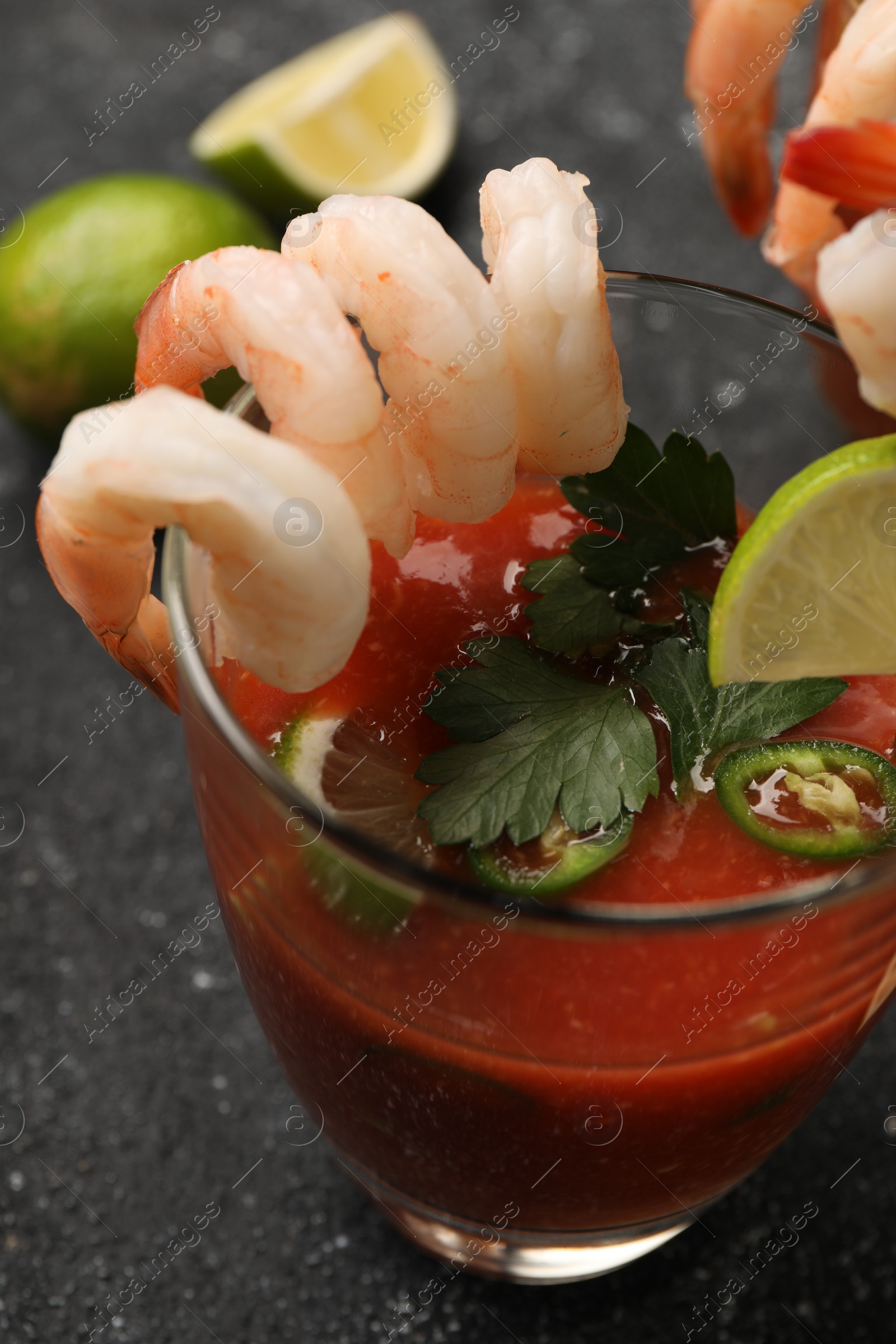 Photo of Tasty shrimp cocktail with sauce in glass on grey textured table, closeup