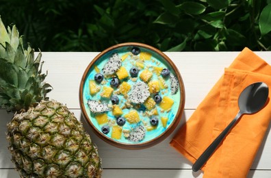 Photo of Delicious smoothie bowl with fresh fruits, blueberries and oatmeal served on white wooden table outdoors, flat lay