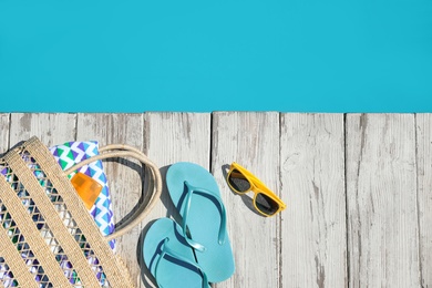 Photo of Beach accessories on wooden deck near outdoor swimming pool, flat lay. Space for text