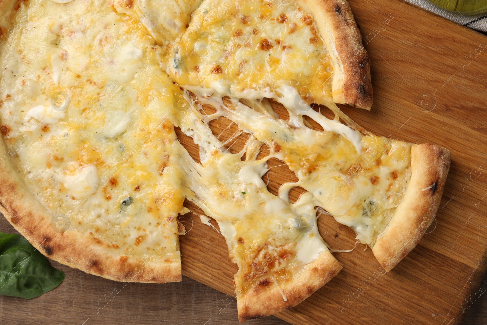 Photo of Delicious cut cheese pizza on wooden table, top view