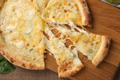 Delicious cut cheese pizza on wooden table, top view