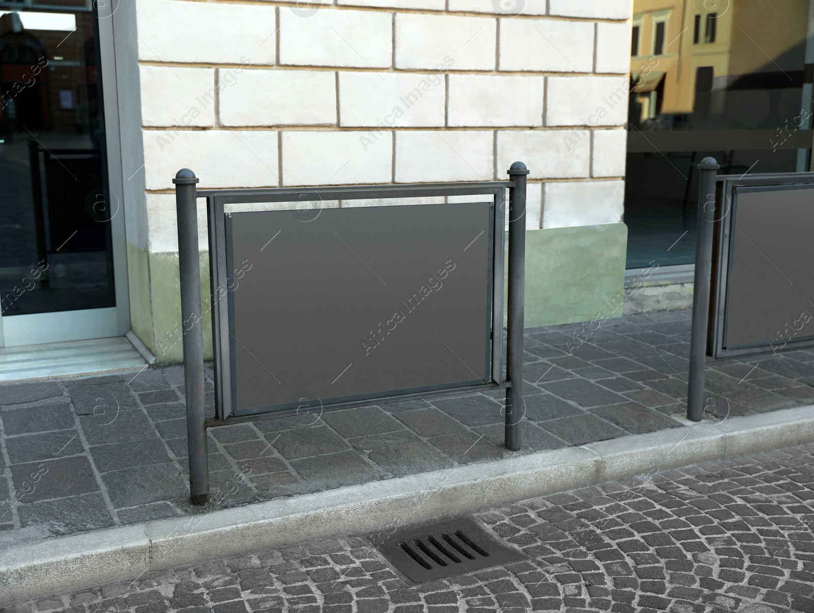 Photo of Blank advertising board on city street near building. Mockup for design