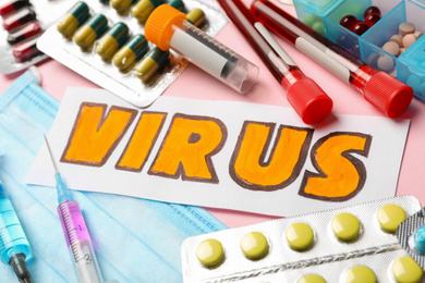 Photo of Word VIRUS and medicines on pink background, closeup