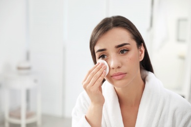 Photo of Young woman with eyelash loss problem removing makeup indoors