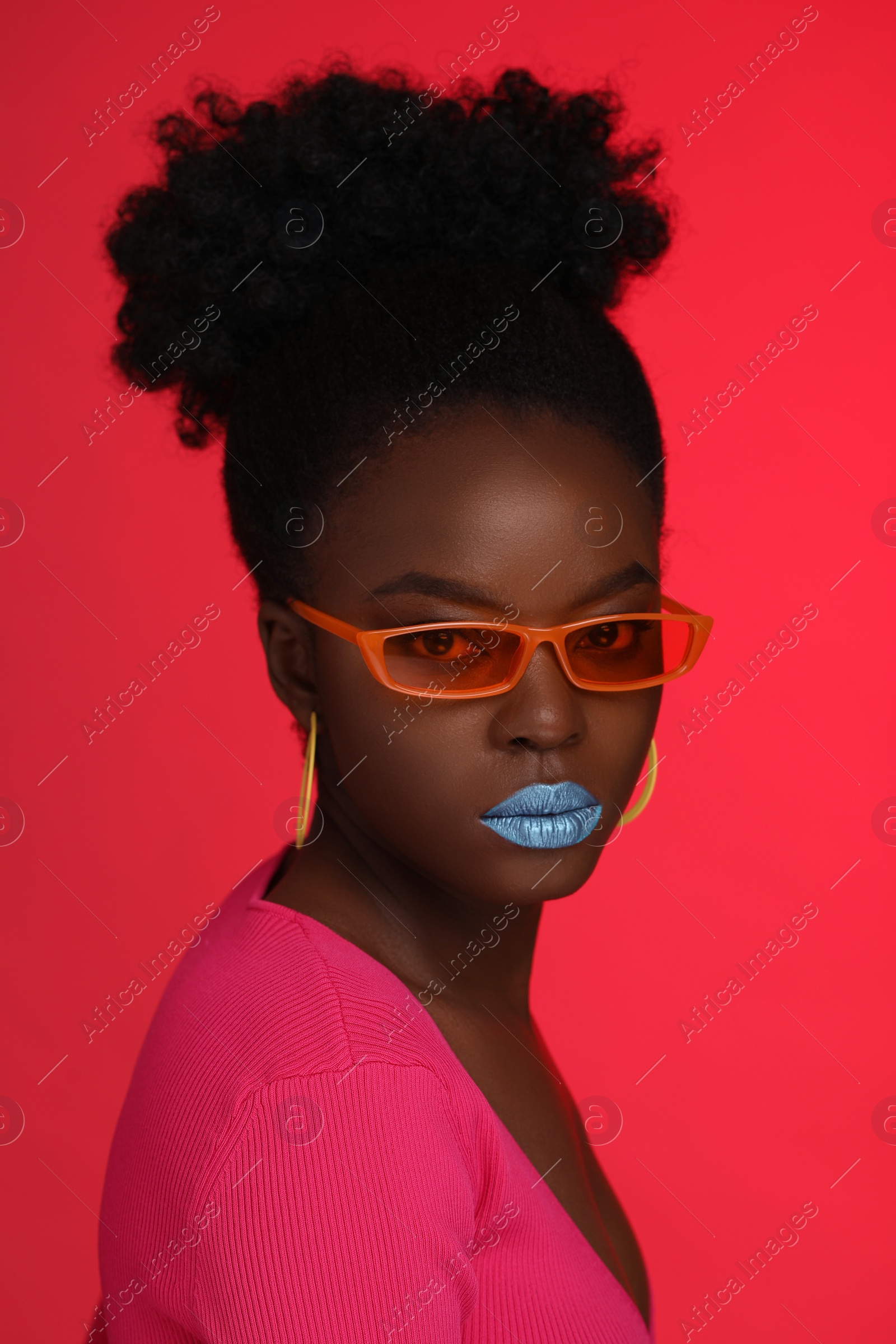 Photo of Fashionable portrait of beautiful woman with stylish sunglasses on coral background