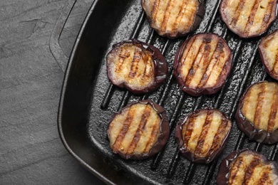 Photo of Delicious grilled eggplant slices in pan on black table, top view