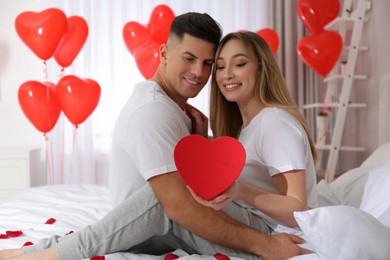 Photo of Lovely couple with gift in room. Valentine's day celebration