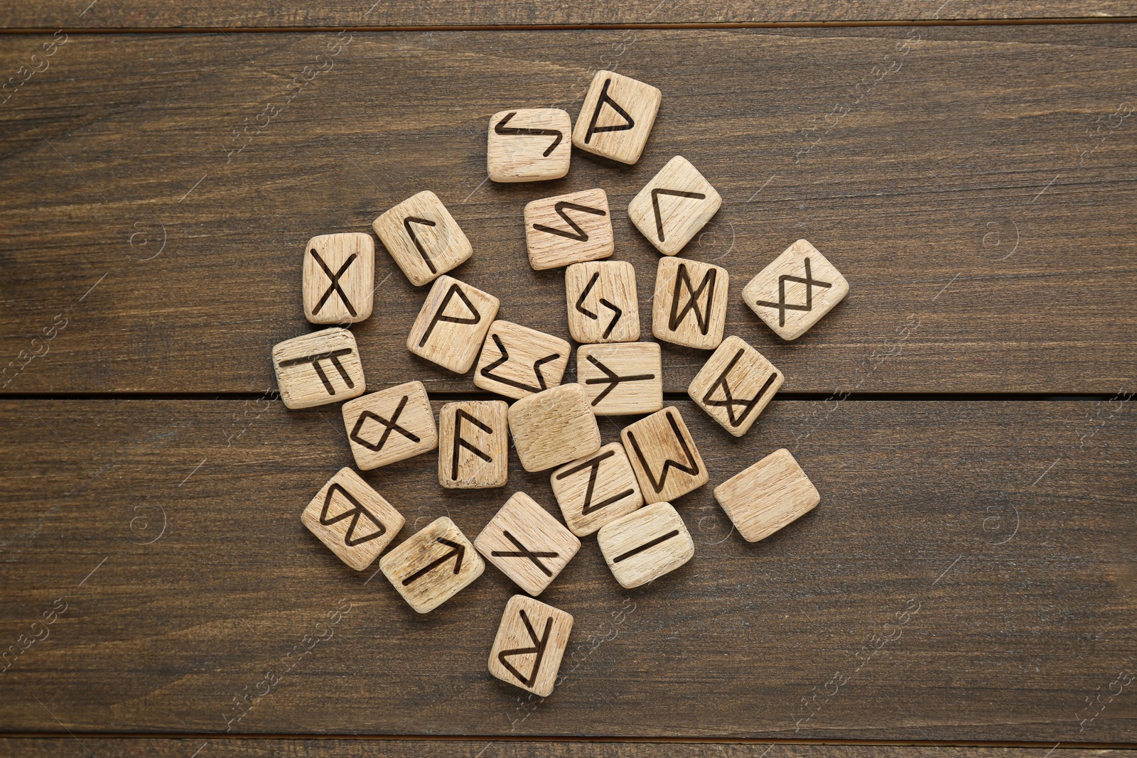 Photo of Runes with different symbols on wooden table, flat lay
