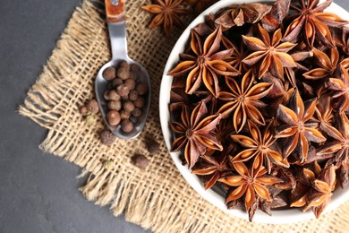 Photo of Bowl with aromatic anise stars and pepper on dark table, flat lay