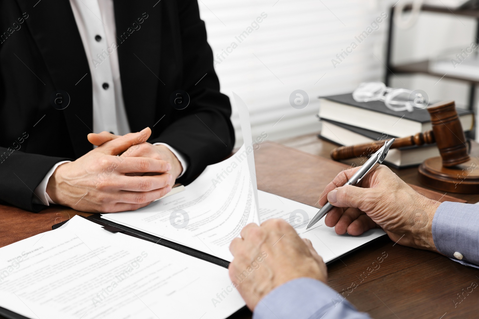 Photo of Senior man signing document in lawyer's office, closeup