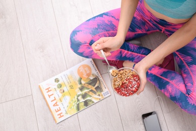 Photo of Young woman in fitness clothes having healthy breakfast at home, top view