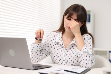 Overwhelmed woman sitting at table with laptop in office