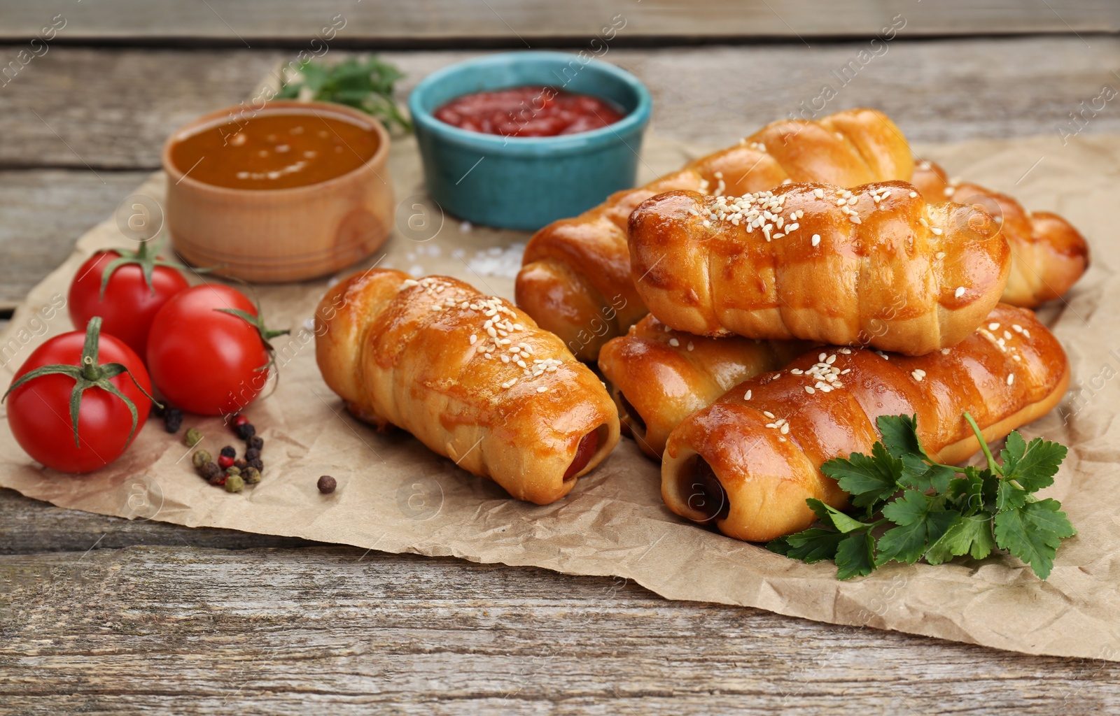 Photo of Delicious sausage rolls and ingredients on wooden table