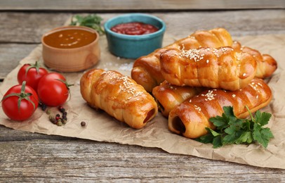 Photo of Delicious sausage rolls and ingredients on wooden table