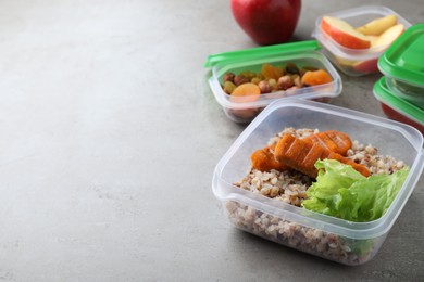 Set of plastic containers with fresh food on light grey table, space for text