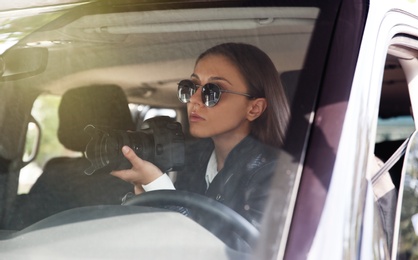 Private detective with camera spying from car