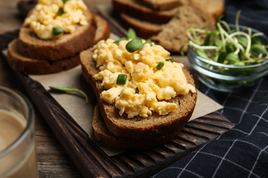 Photo of Tasty scrambled egg sandwiches on wooden board