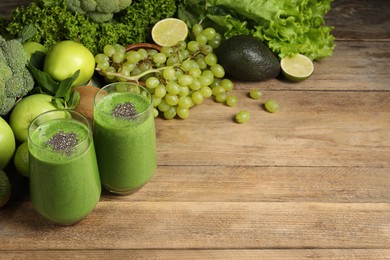 Photo of Glasses of fresh green smoothie and ingredients on wooden table, space for text