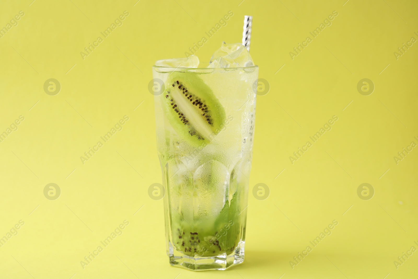 Photo of Glass of refreshing drink with kiwi on yellow background