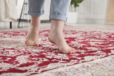 Photo of Woman standing on carpet with pattern at home, closeup. Space for text