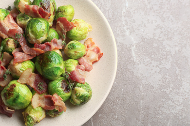 Photo of Delicious Brussels sprouts with bacon on marble table, top view. Space for text