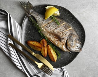 Photo of Delicious baked fish served on grey table, top view. Seafood