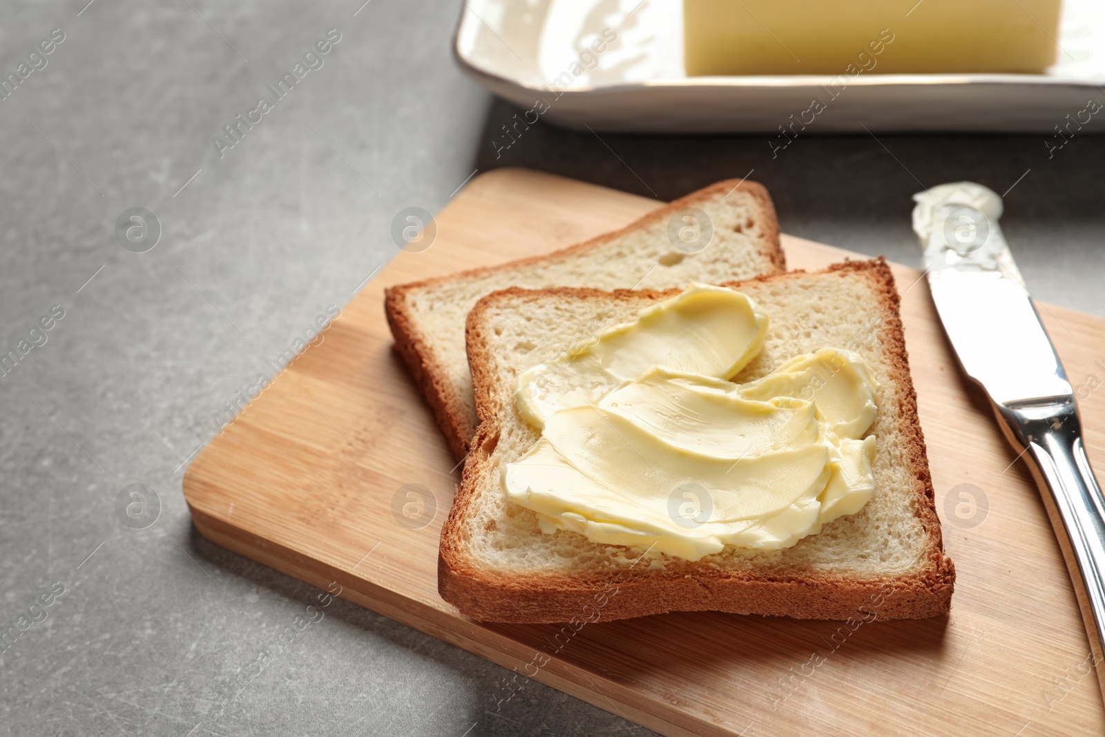 Photo of Tasty bread with butter and knife on wooden board