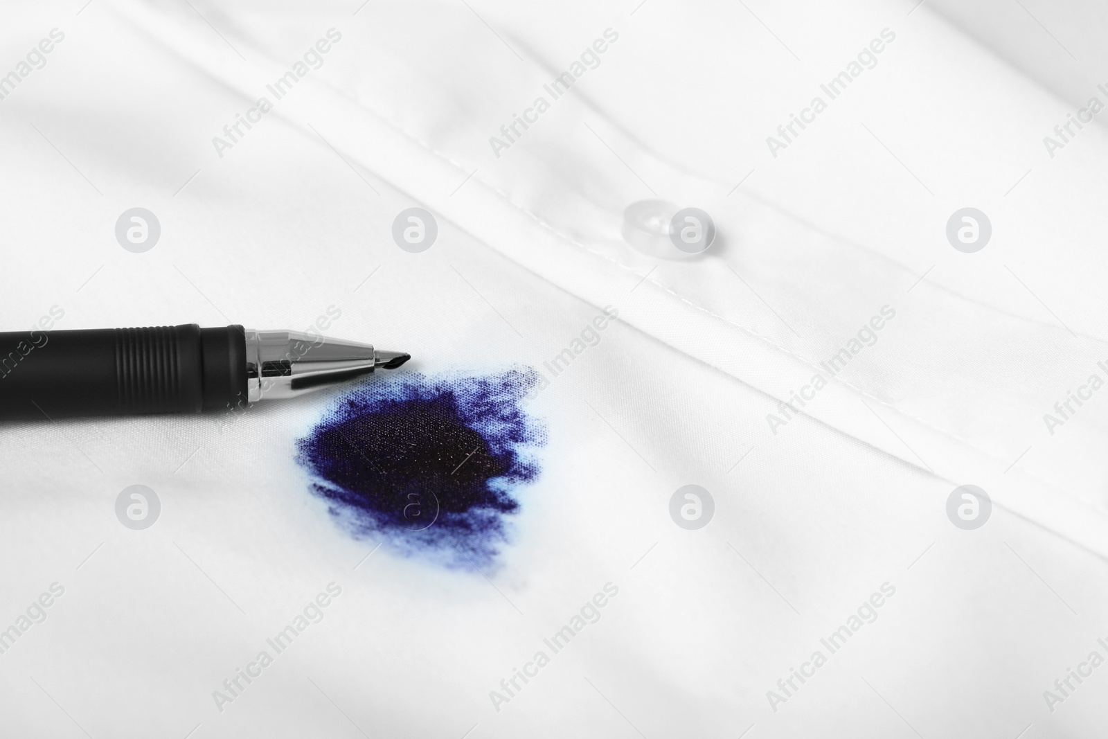 Photo of Pen and stain of blue ink on white shirt, closeup. Space for text