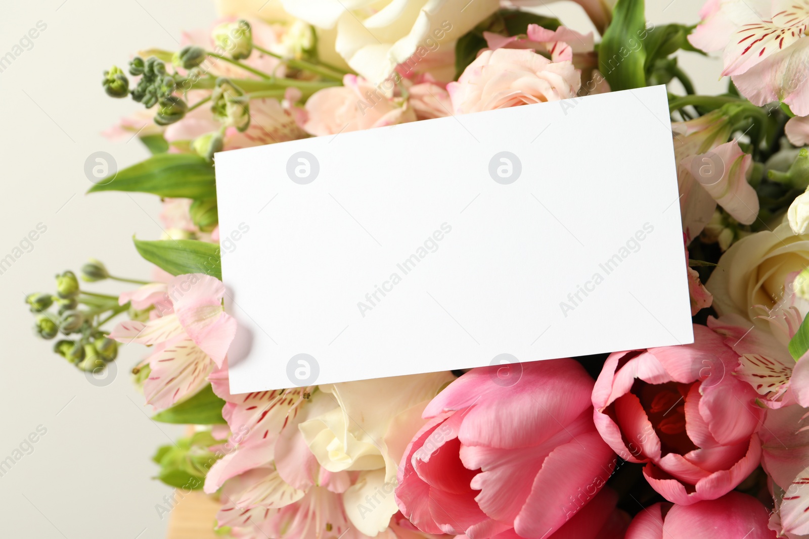 Photo of Happy Mother's Day. Beautiful flowers with blank card on light background, closeup