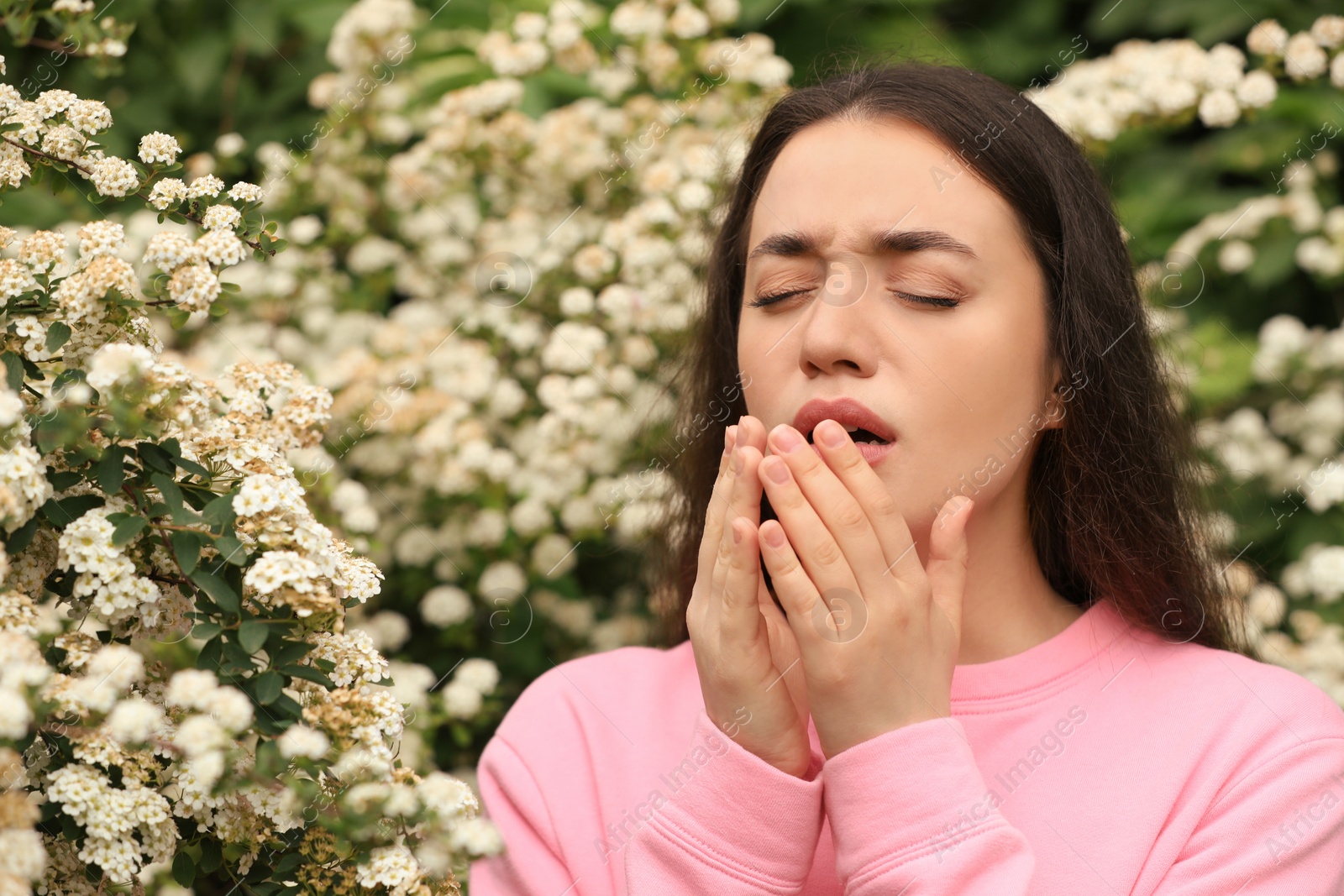 Photo of Woman suffering from seasonal pollen allergy near blossoming tree on spring day