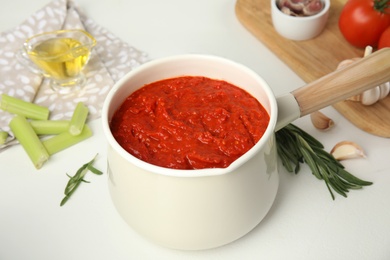 Photo of Delicious tomato sauce in pan on white table