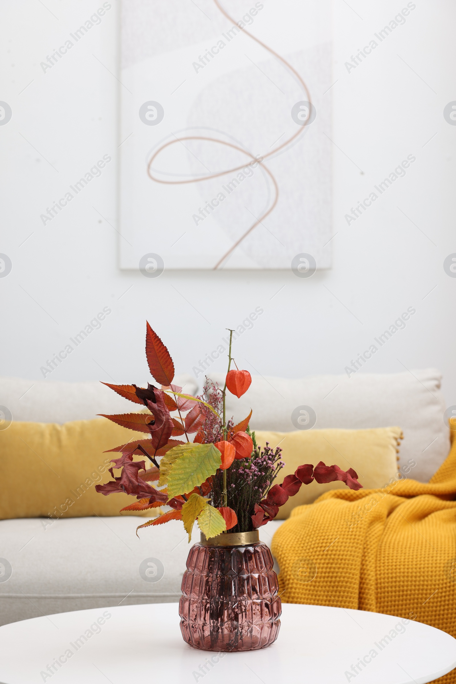 Photo of Vase with bouquet on side table and comfortable sofa in living room