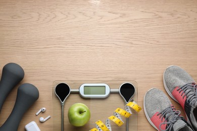 Flat lay composition with electronic scales and measuring tape on wooden background, space for text