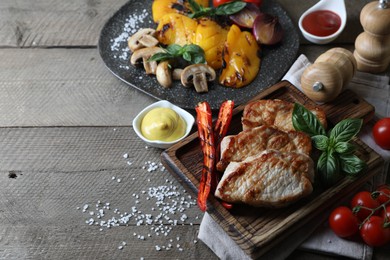 Delicious grilled meat and vegetables served on wooden table. Space for text