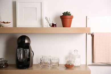 Photo of Modern coffeemaker on wooden table near white wall