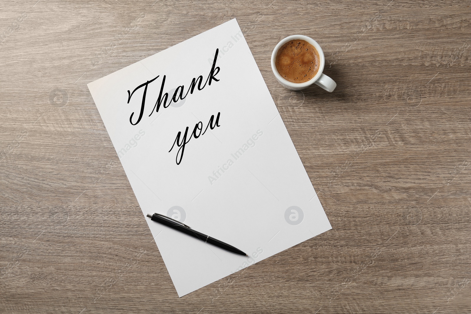 Image of Paper with phrase Thank You, pen and cup of coffee on wooden table, flat lay