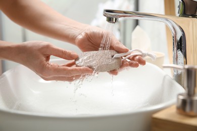 Photo of Woman pouring water onto pumice stone in bathroom, closeup