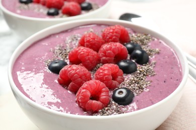 Photo of Delicious acai smoothie with raspberries and chia seeds in bowl on table, closeup