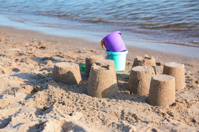 Photo of Little sand figures and plastic toys on beach near sea. Space for text