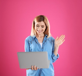 Woman using laptop for video chat on color background