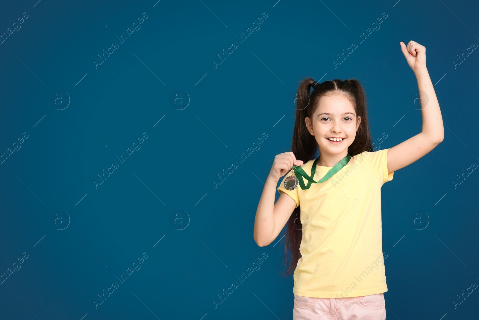 Photo of Happy girl with golden medal on dark blue background. Space for text