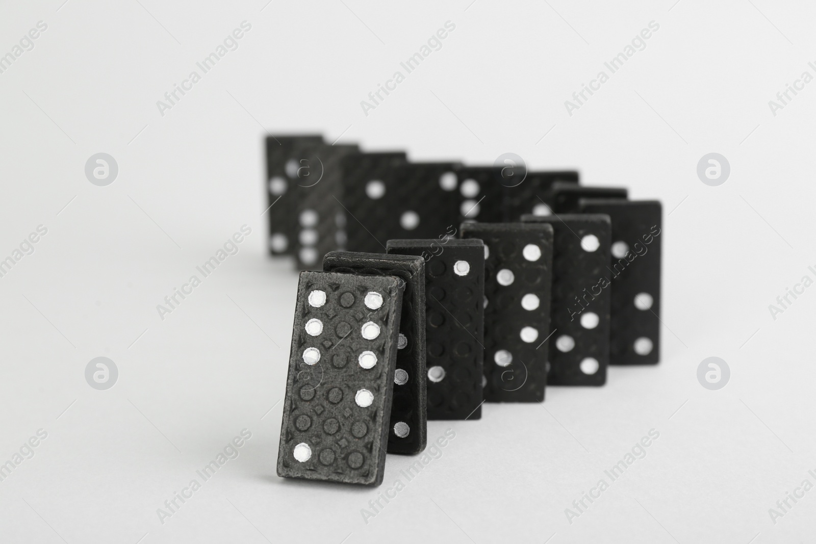 Photo of Black domino tiles falling on white background