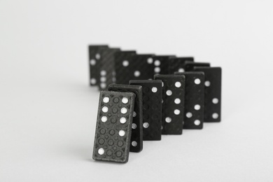 Black domino tiles falling on white background