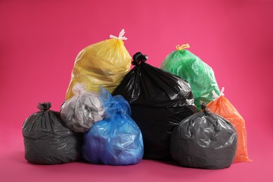 Photo of Trash bags full of garbage on pink background