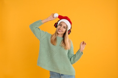 Photo of Happy woman with headphones on yellow background. Christmas music