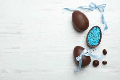 Photo of Flat lay composition with chocolate Easter eggs on wooden background, space for text