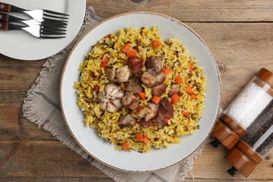 Delicious pilaf and spices on wooden table, flat lay