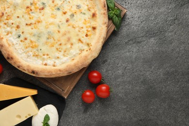 Photo of Delicious cheese pizza and ingredients on dark grey table, flat lay. Space for text