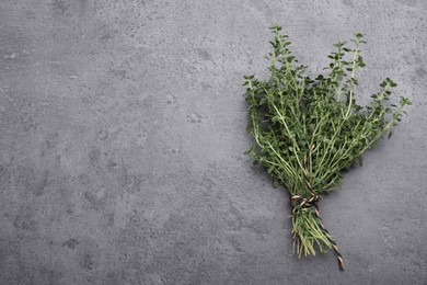 Photo of Bunch of aromatic thyme on grey table, top view. Space for text