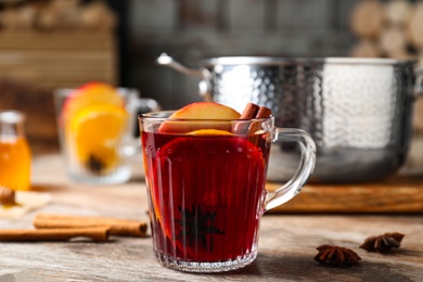 Photo of Delicious mulled wine and ingredients on wooden table, closeup